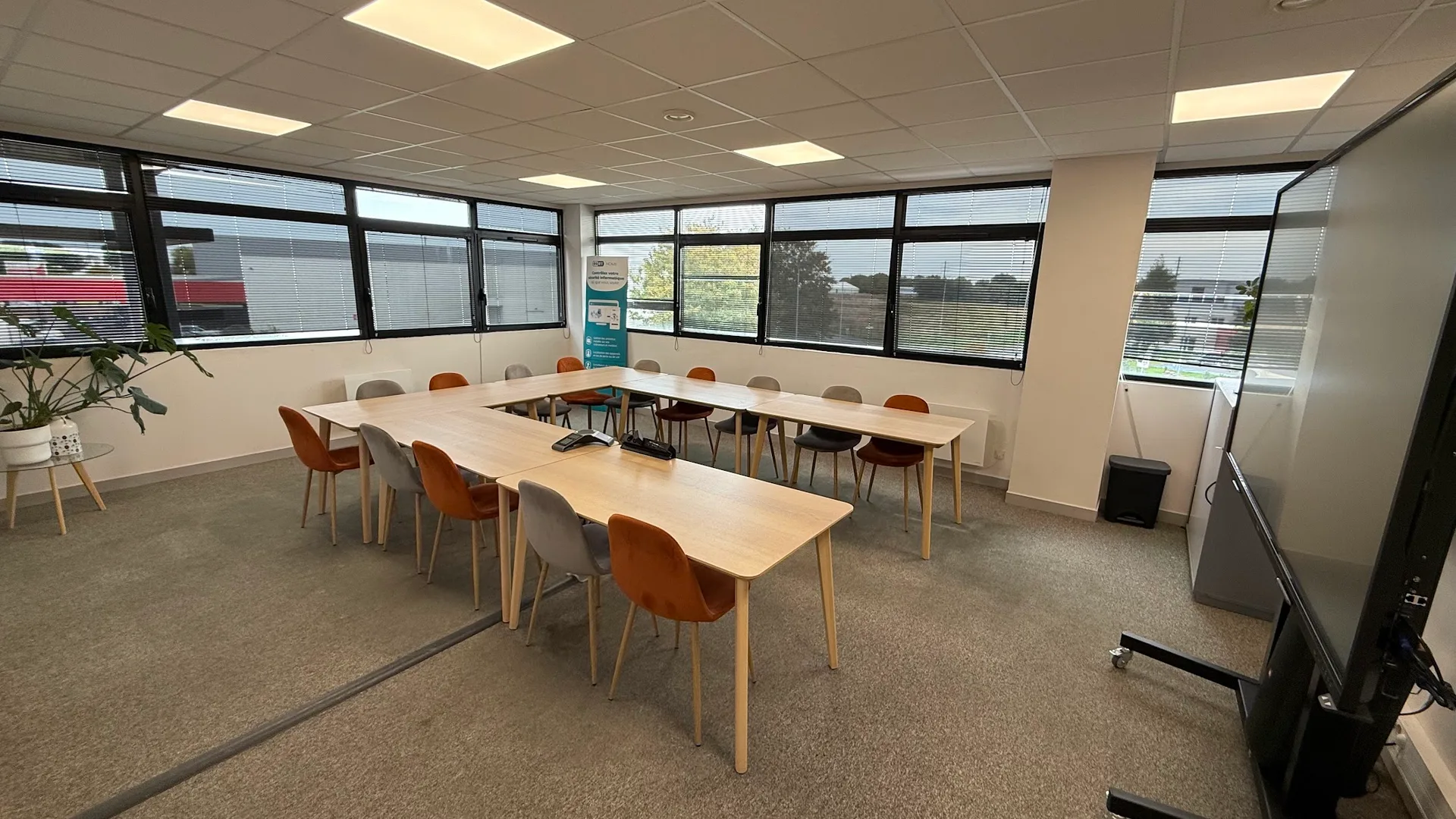 La grande salle de réunion Coworkom, avec ses tables, ses fauteuils et son écran